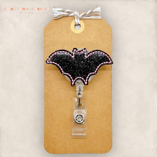 glittery black bat with pink edges badge reel