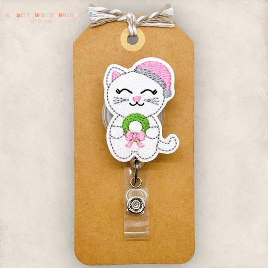 white cat with pink santa hat and wreath embroidered badge reel topper