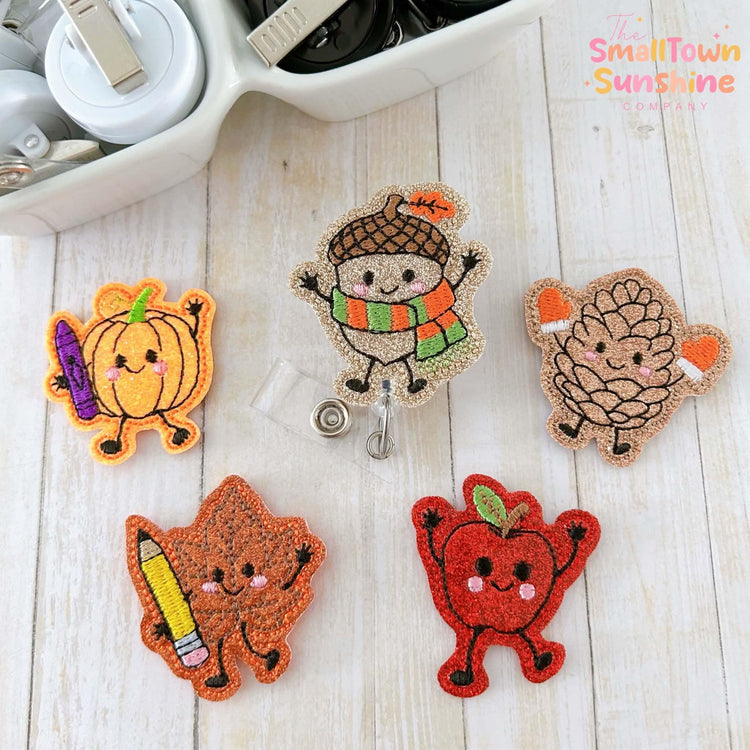 a collection of five colorful, embroidered badges or patches, each depicting a different animal or character, arranged on a wooden surface.